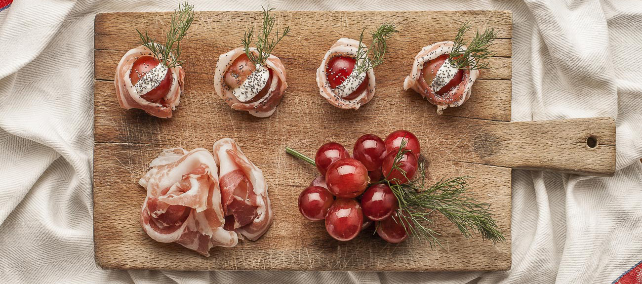 Häppchen aus gefaltetem Bauchspeck mit Weintrauben und Robiola-Käse